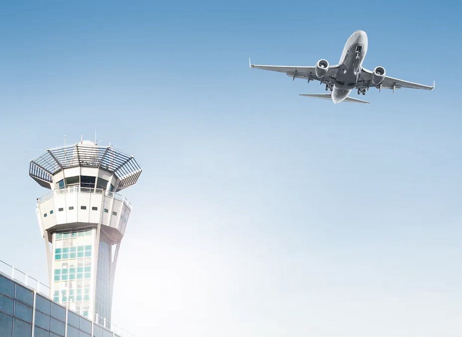 Airplane taking off above an airport control tower, symbolizing private chauffeur transfers from CDG, Orly and Paris airports to Disneyland Paris.
